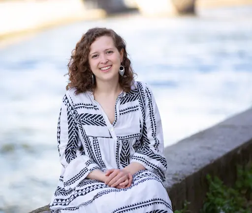 Valentine, accompagnante périnatale à Caen, souriante assise près de la mer en Normandie